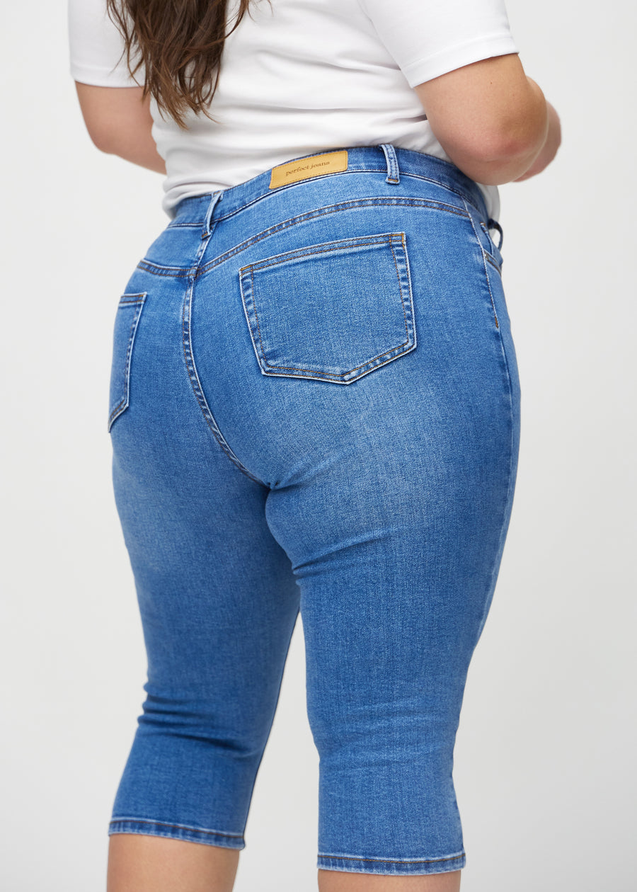 Skinny-Capris für Damen in blauem Denim, Farbe Rivers. Nahaufnahme von hinten an einem Plus-Size-Model, zeigt Taschen und Nähte.
