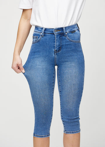 Skinny-Capris für Damen in blauem Denim, Farbe Rivers. Ein Model dehnt den Stoff, um den Stretch zu zeigen.