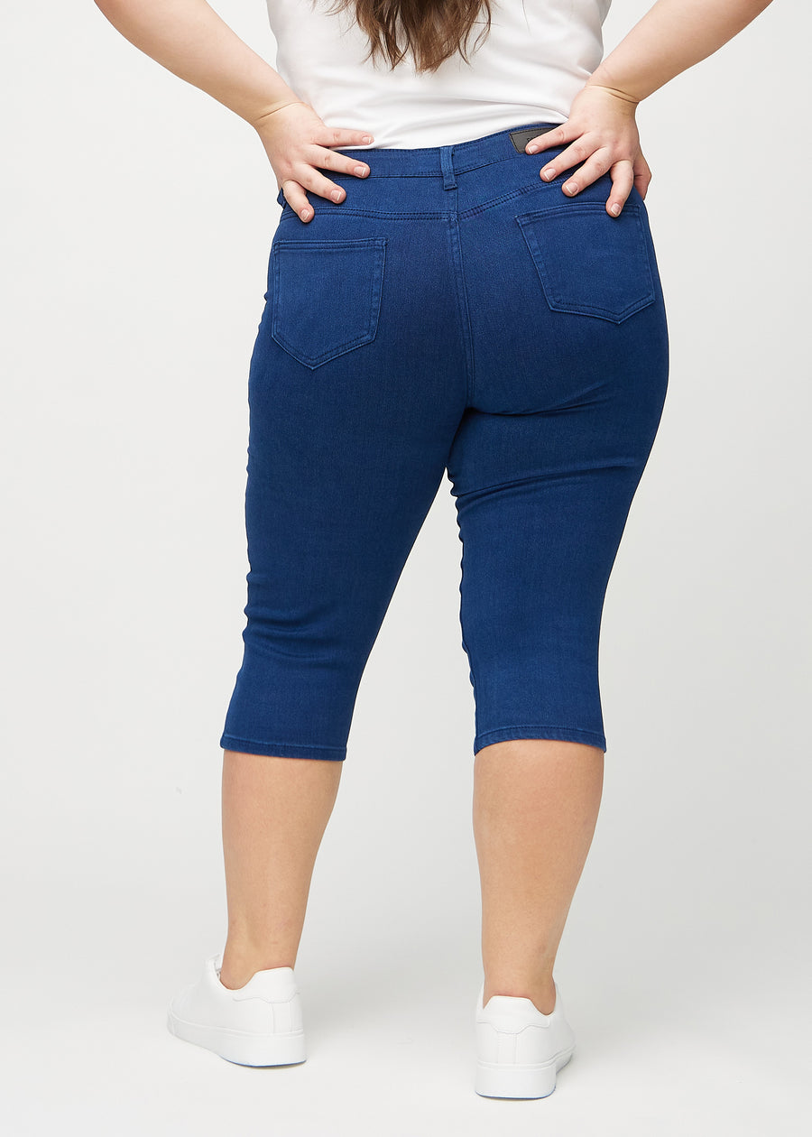 Skinny-Capris für Damen in dunkelblauem Jeansstoff, Farbe Royals. Rückansicht an einem Plus-Size-Model, zeigt die Passform und Gesäßtaschen.
