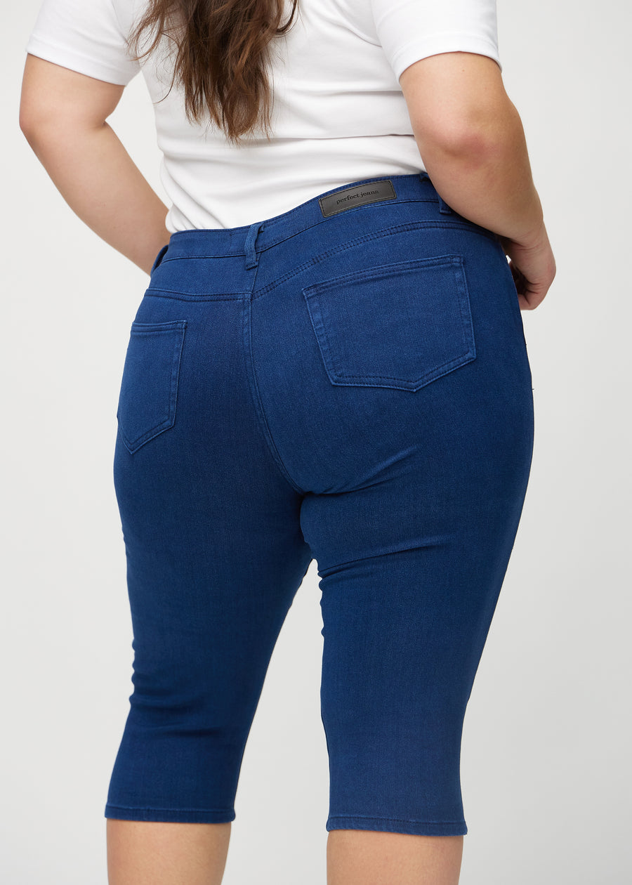 Skinny-Capris für Damen in dunkelblauem Jeansstoff, Farbe Royals. Nahaufnahme von hinten an einem Plus-Size-Model, zeigt Taschen und Nähte.