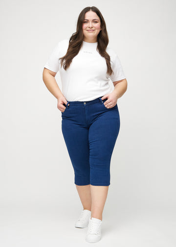 Skinny-Capris für Damen in dunkelblauem Jeansstoff, Farbe Royals. Ganzkörperansicht eines Plus-Size-Models in den Capris.