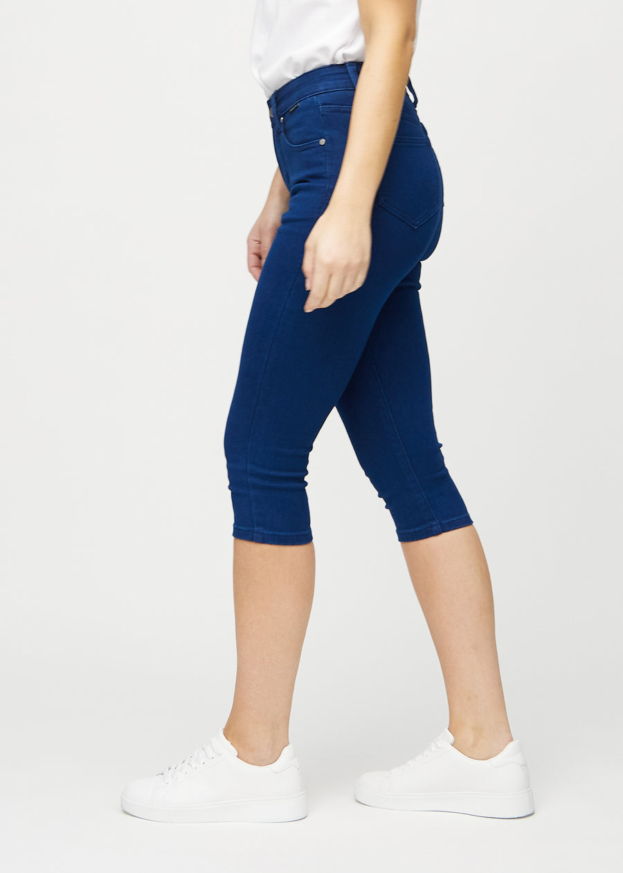 Skinny-Capris für Damen in dunkelblauem Jeansstoff, Farbe Royals. Seitenansicht an einem Model, die figurbetonte Passform ist zu sehen.