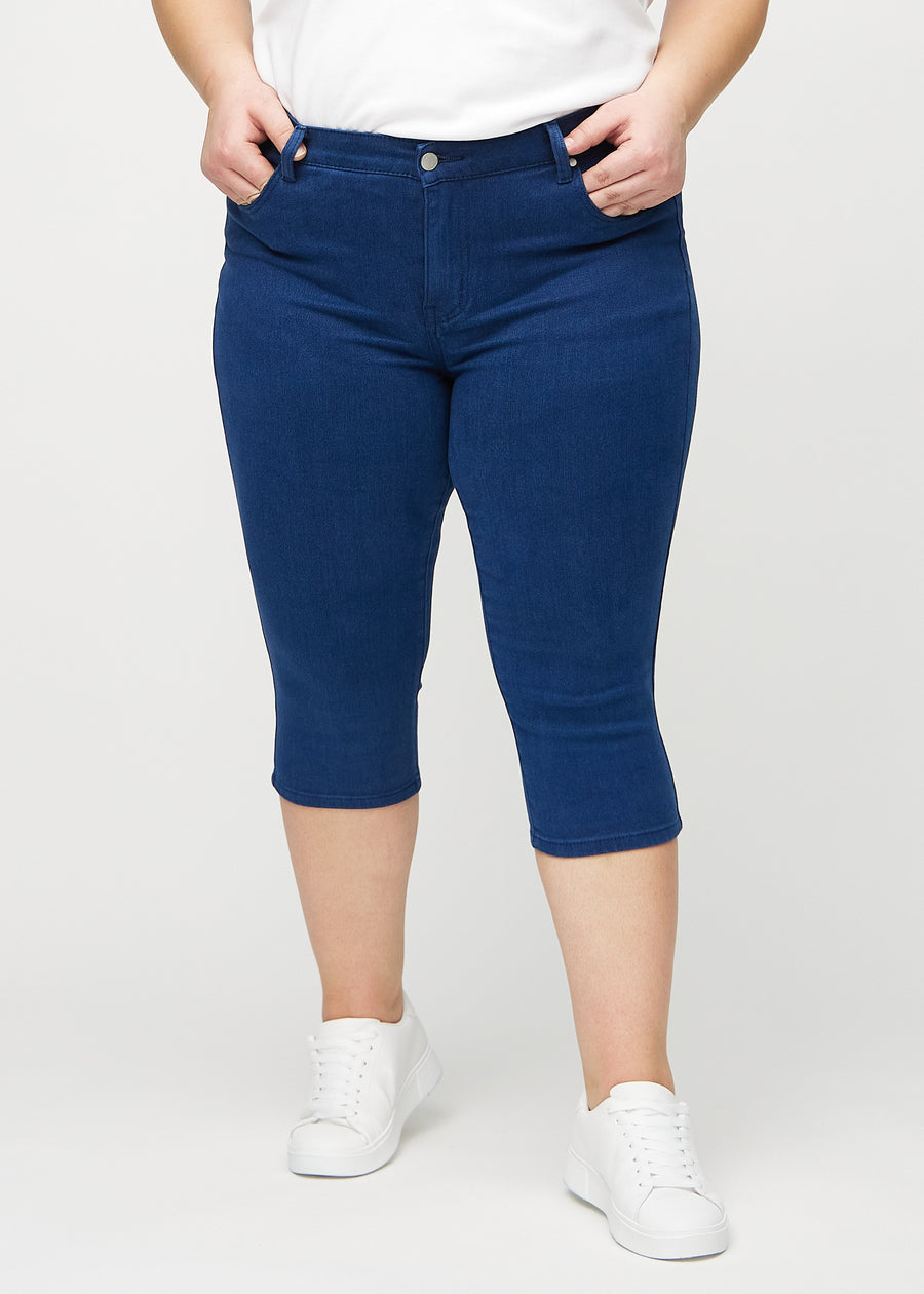 Skinny-Capris für Damen in dunkelblauem Jeansstoff, Farbe Royals. Vorderansicht an einem Plus-Size-Model, eng geschnitten bis knapp unter das Knie.
