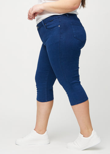 Skinny-Capris für Damen in dunkelblauem Jeansstoff, Farbe Royals. Seitenansicht an einem Plus-Size-Model, die figurbetonte Passform ist zu sehen.