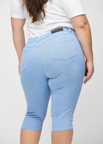 Skinny-Capris für Damen in hellblauem Jeansstoff, Farbe Skies. Nahaufnahme von hinten an einem Plus-Size-Model, zeigt Taschen und Nähte.
