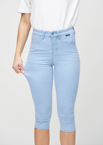 Skinny-Capris für Damen in hellblauem Jeansstoff, Farbe Skies. Ein Model dehnt den Stoff, um den Stretch zu zeigen.