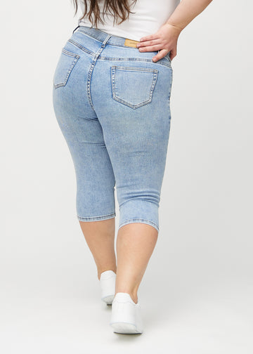 Skinny-Capris für Damen in hellblauem Denim, Farbe Waves. Rückansicht an einem Plus-Size-Model, zeigt die Passform und Gesäßtaschen.