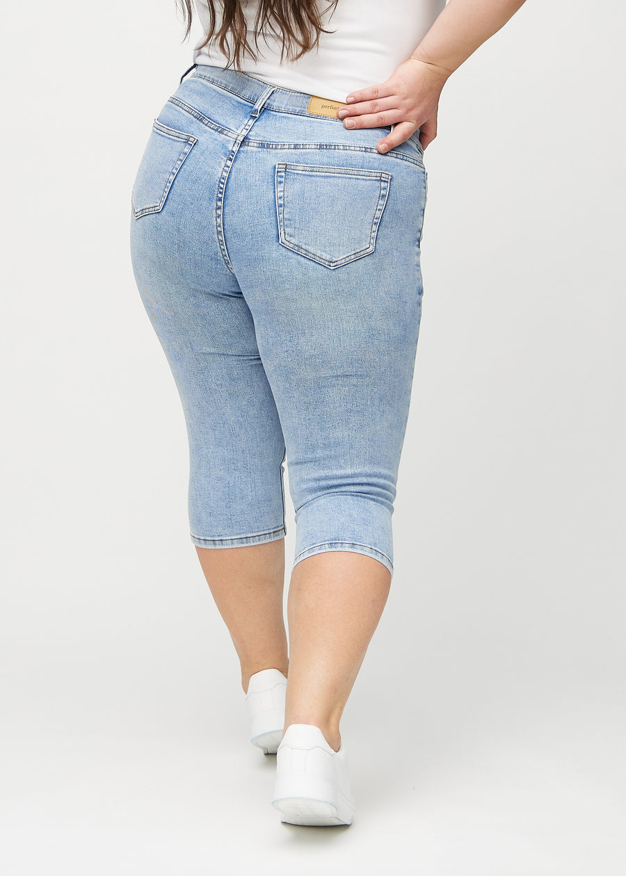 Skinny-Capris für Damen in hellblauem Denim, Farbe Waves. Rückansicht an einem Plus-Size-Model, zeigt die Passform und Gesäßtaschen.