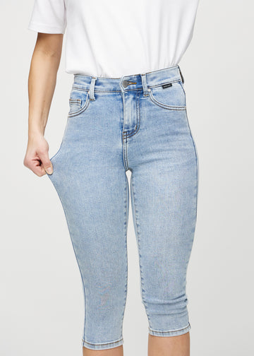 Skinny-Capris für Damen in hellblauem Denim, Farbe Waves. Ein Model dehnt den Stoff, um den Stretch zu zeigen.