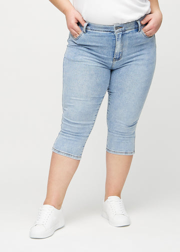 Skinny-Capris für Damen in hellblauem Denim, Farbe Waves. Vorderansicht an einem Plus-Size-Model, eng geschnitten bis knapp unter das Knie.