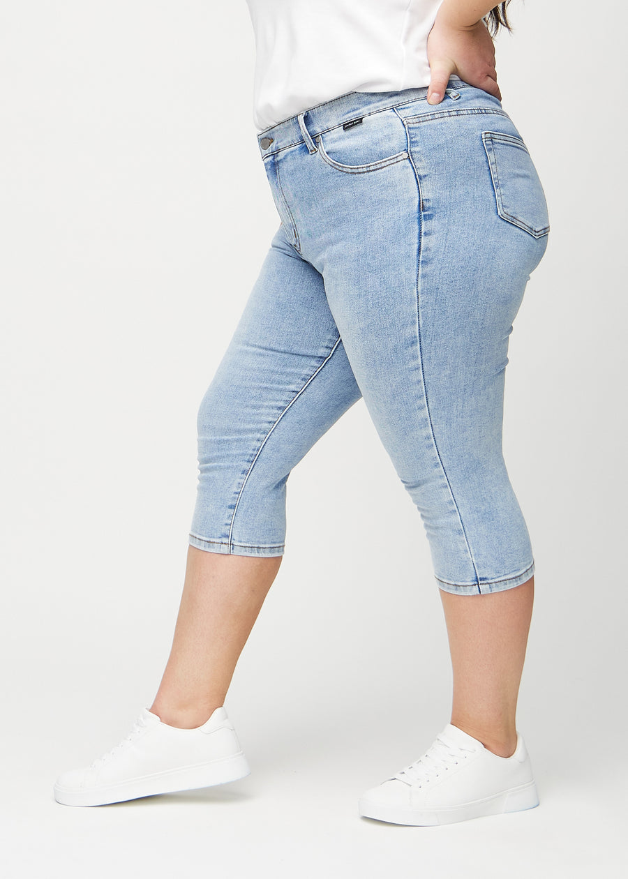 Skinny-Capris für Damen in hellblauem Denim, Farbe Waves. Seitenansicht an einem Plus-Size-Model, die figurbetonte Passform ist zu sehen.