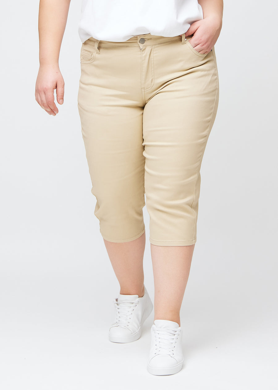 Slim-Capris für Damen aus beigefarbenem Jeansstoff, Farbe Gazelles. Vorderansicht an einem Plus-Size-Model, figurbetonter Schnitt bis knapp unter das Knie.