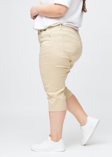 Slim-Capris für Damen aus beigefarbenem Jeansstoff, Farbe Gazelles. Seitenansicht an einem Plus-Size-Model, figurbetonter Schnitt und mittelhoher Bund (Mid Rise).