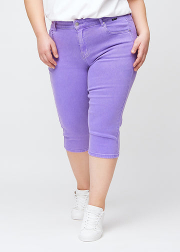 Slim-Capris für Damen aus pastellviolettem Jeansstoff, Farbe Lavenders. Vorderansicht an einem Plus-Size-Model, figurbetonter Schnitt bis knapp unter das Knie.