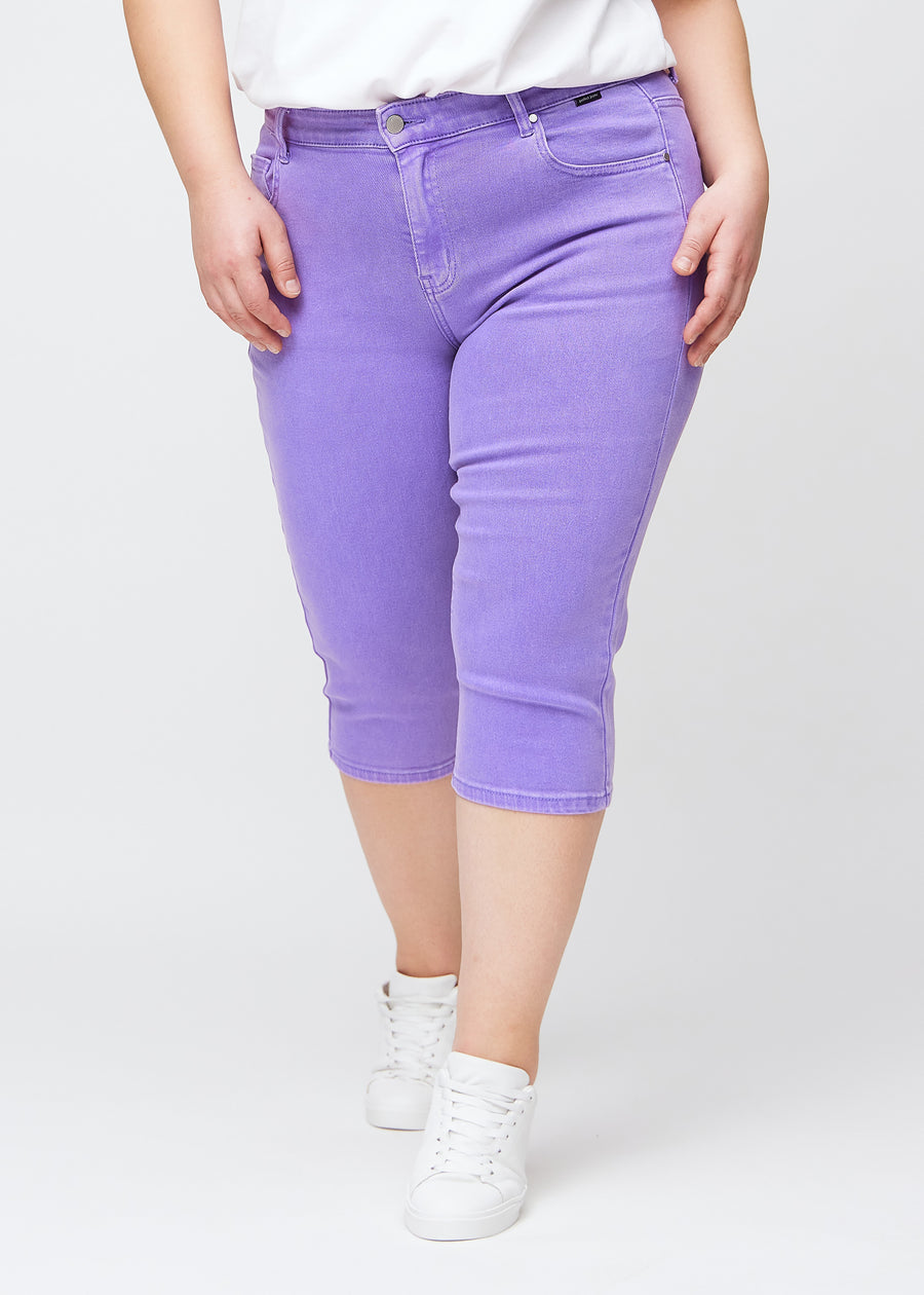 Slim-Capris für Damen aus pastellviolettem Jeansstoff, Farbe Lavenders. Vorderansicht an einem Plus-Size-Model, figurbetonter Schnitt bis knapp unter das Knie.