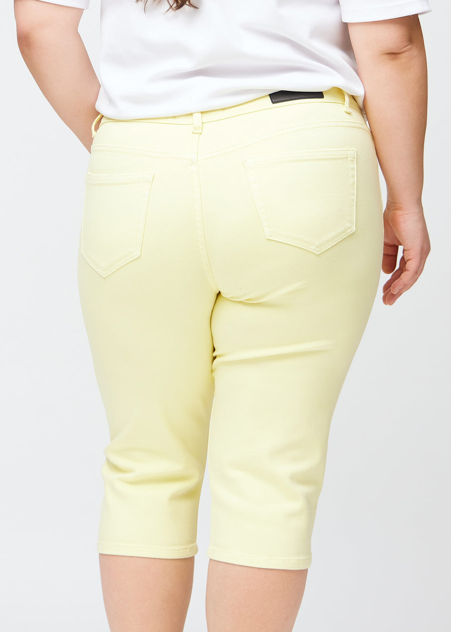 Nahes Bild der Rückseite eines Plus-Size-Models in hellgelben slim Capris, Fokus auf Details an Taschen und Nähten.