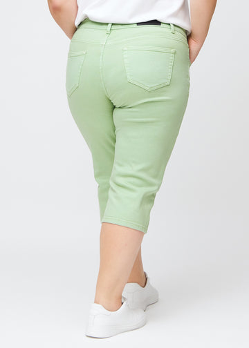 Hellgrüne slim Capris von hinten an einem Plus-Size-Model gesehen, deutliches Bild des gesamten Produkts und der Taschen.
