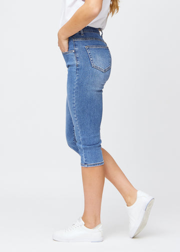 Slim-Capris für Damen aus blauem Denim, Farbe Rivers. Seitenansicht an einem Model, figurbetonter Schnitt und mittelhoher Bund (Mid Rise).