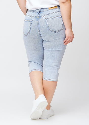 Slim-Capris für Damen aus hellblauem Denim, Farbe Waves. Rückansicht an einem Plus-Size-Model, zeigt Passform, Länge und Gesäßtaschen.