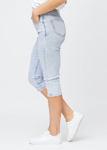 Slim-Capris für Damen aus hellblauem Denim, Farbe Waves. Seitenansicht an einem Model, figurbetonter Schnitt und mittelhoher Bund (Mid Rise).