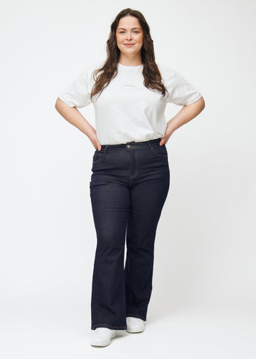 Ganzkörperbild eines Plus-Size-Models in tief dunkelblauer Denim jeans für Damen in der Farbe Midnights mit Bootcut-Passform.