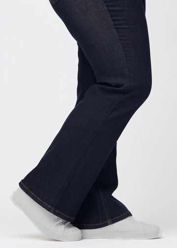 Tief dunkelblaue Denim jeans für Damen in der Farbe Midnights mit Bootcut-Passform in Nahaufnahme an den Knöcheln eines Plus-Size-Models gezeigt, um den leichten Schlag zu zeigen.