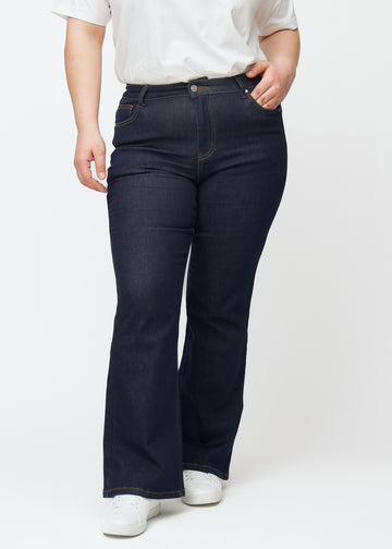 Tief dunkelblaue Denim jeans für Damen in der Farbe Midnights mit Bootcut-Passform, von vorn an einem Plus-Size-Model gezeigt.