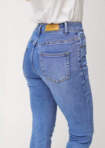 Blaue Mid-Rise-Bootcut-Jeans in der Farbe Rivers. Nahaufnahme der Rückseite an einem Model, um Details zu zeigen.