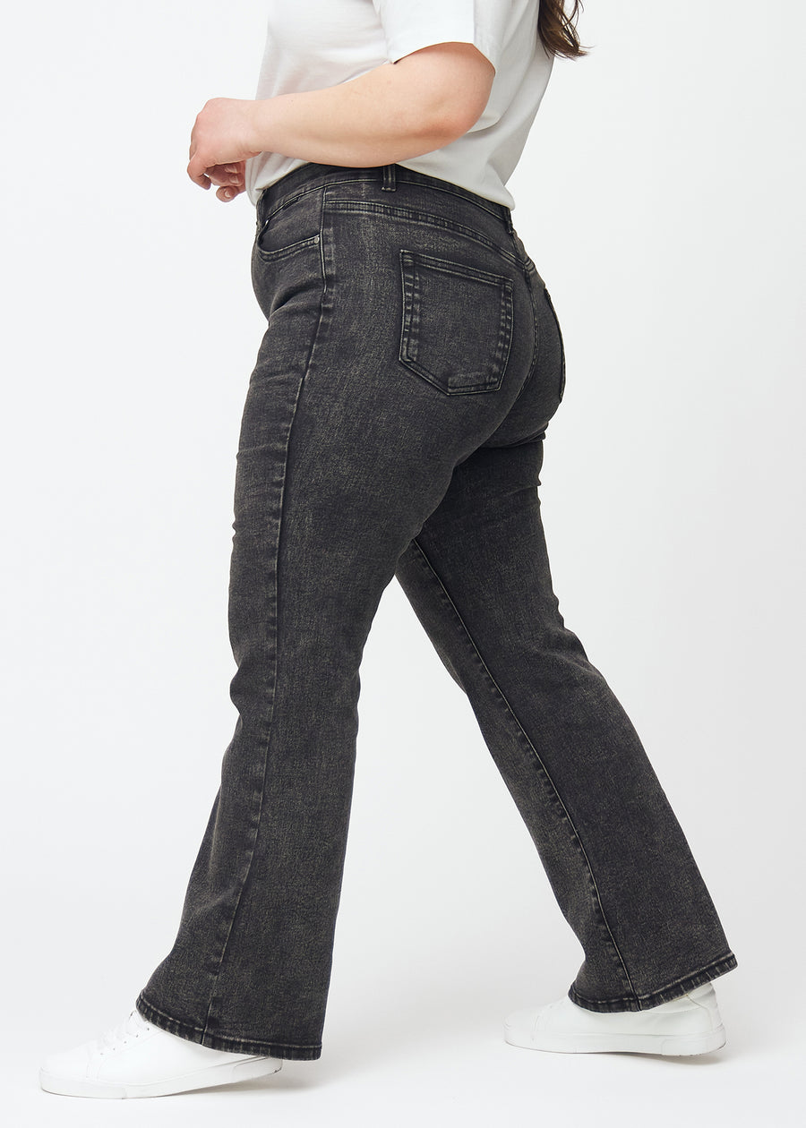 Dunkelgraue Mid-Rise-Bootcut-Jeans in der Farbe Shadows. Seitenansicht an einem Plus-Size-Model.