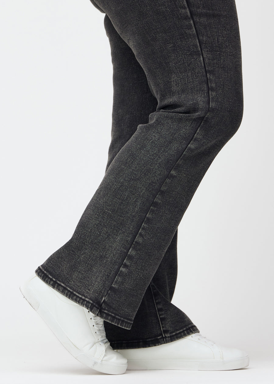 Dunkelgraue Mid-Rise-Bootcut-Jeans in der Farbe Shadows. Nahaufnahme am Knöchel eines Plus-Size-Model, um den leichten Schlag am Beinabschluss zu zeigen.