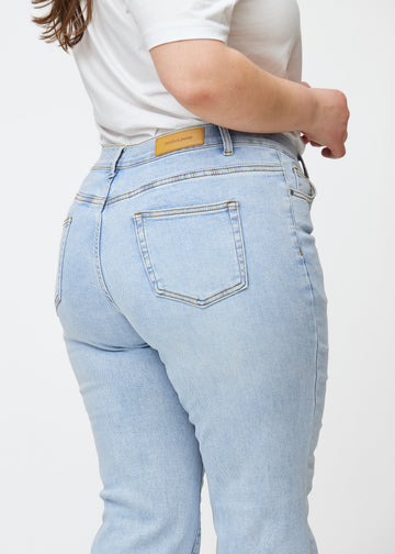 Hellblaue Mid-Rise-Bootcut-Jeans in der Farbe Waves. Nahaufnahme der Rückseite an einem Plus-Size-Model, um Details zu zeigen.