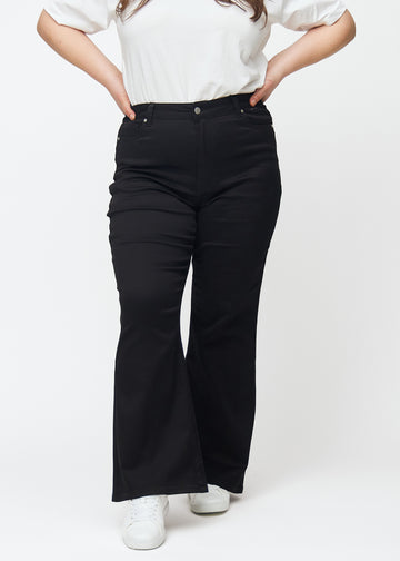 Schwarze hochtaillierte Bootcut jeans, Modellname Ravens, die von der Taille bis zu den Oberschenkeln eng anliegen und unten leicht ausgestellt sind, an einem Plus-Size-Model, von vorne gesehen.