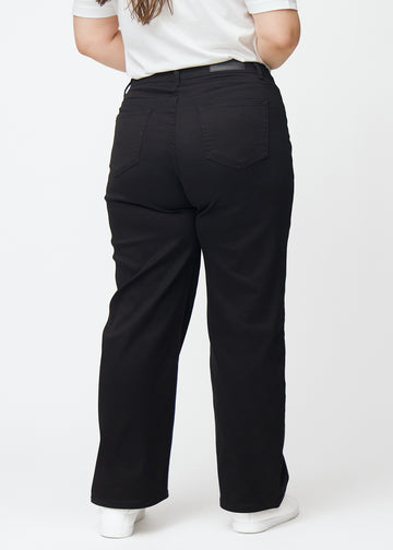 Schwarze hochtaillierte jeans, die an der Taille eng anliegen und eine lockere Passform mit Weite nach unten haben, von hinten an einem Plus-Size-Model gesehen, damit man das gesamte Produkt sehen kann.