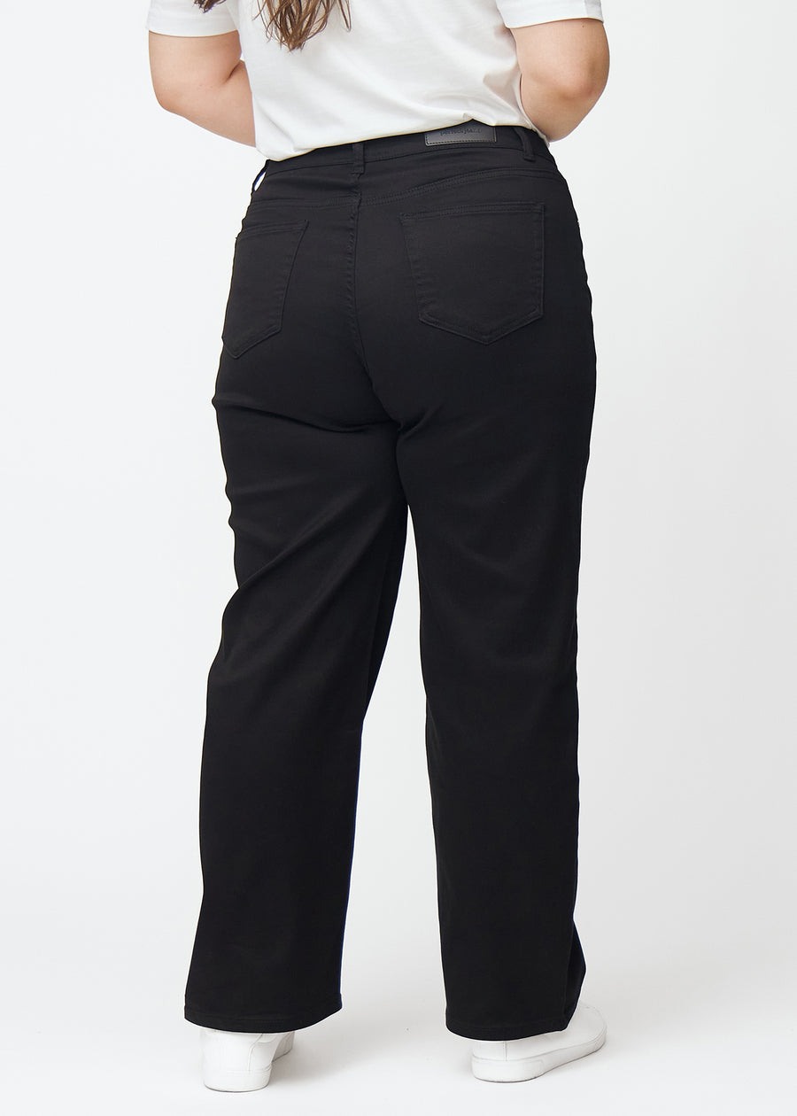 Schwarze hochtaillierte jeans, die an der Taille eng anliegen und eine lockere Passform mit Weite nach unten haben, von hinten an einem Plus-Size-Model gesehen, damit man das gesamte Produkt sehen kann.