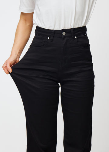 Das Model zieht die Jeans am Oberschenkel, um den Stretch zu zeigen.