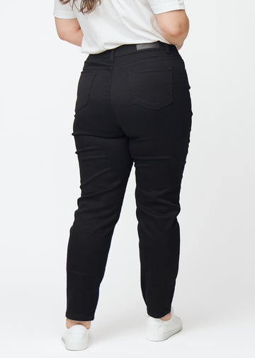 Schwarze hochtaillierte slim jeans von hinten an einem Plus-Size-Model gesehen, damit man das gesamte Produkt sehen kann.
