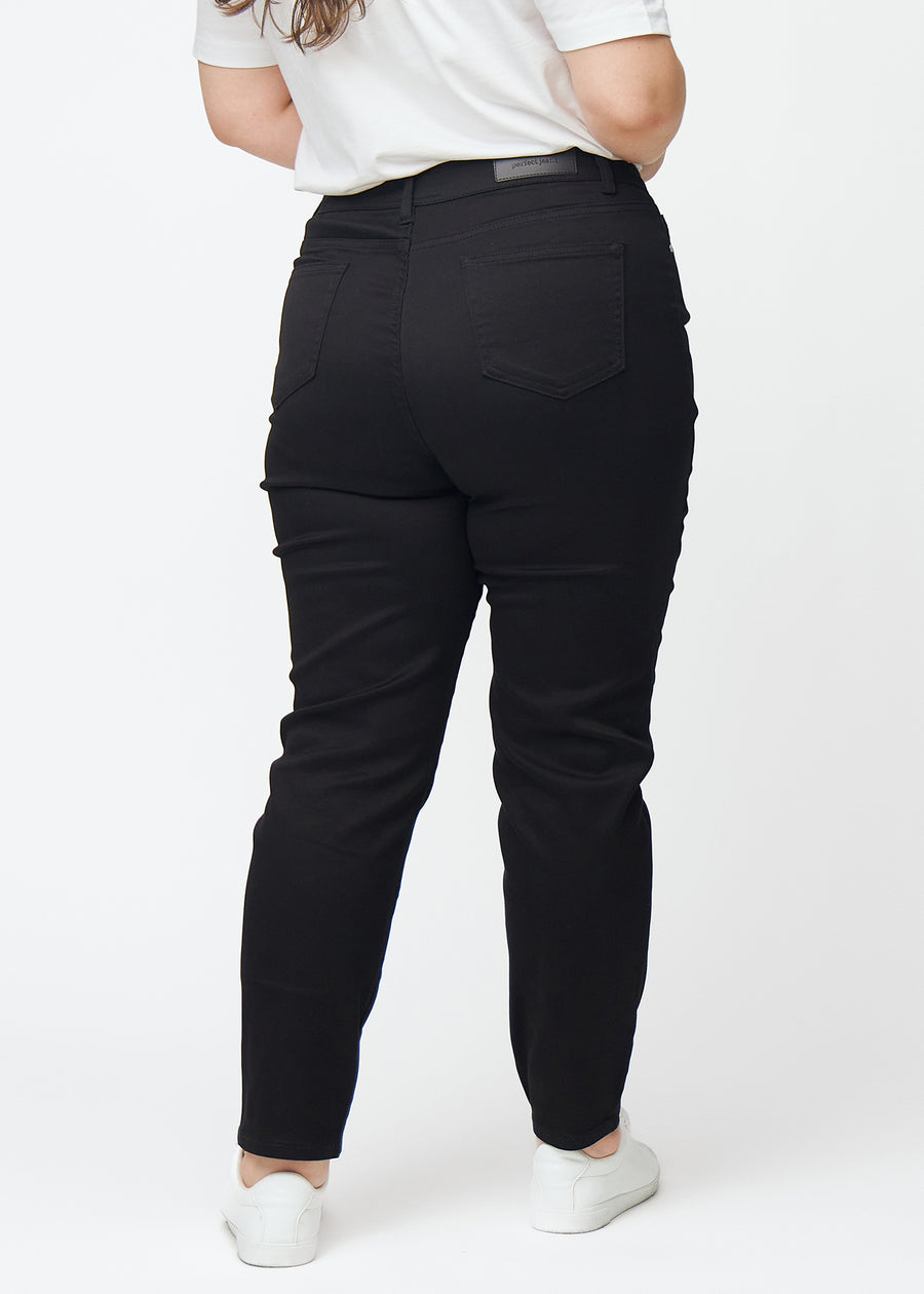 Schwarze hochtaillierte slim jeans von hinten an einem Plus-Size-Model gesehen, damit man das gesamte Produkt sehen kann.