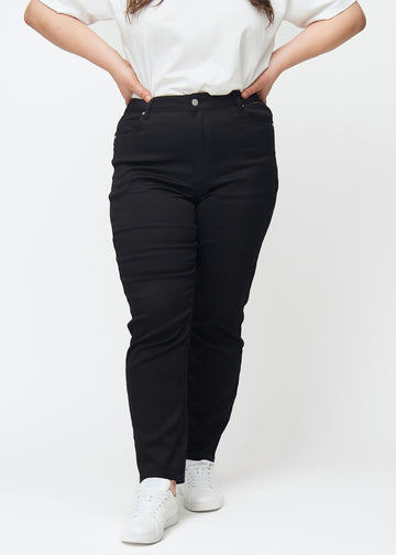 Schwarze hochtaillierte slim jeans, Modellname Ravens, die am Bein eng anliegen, jedoch am Knöchel etwas lockerer sind, an einem Plus-Size-Model, von vorn gesehen.