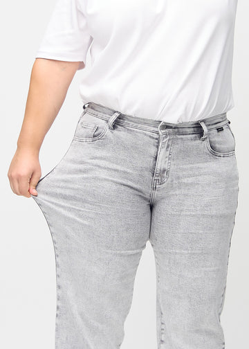Loose-Jeans für Damen in Hellgrau, Farbe Ashes. Ein Plus-Size-Model dehnt den Jeansstoff am Oberschenkel, um den Stretch zu zeigen.