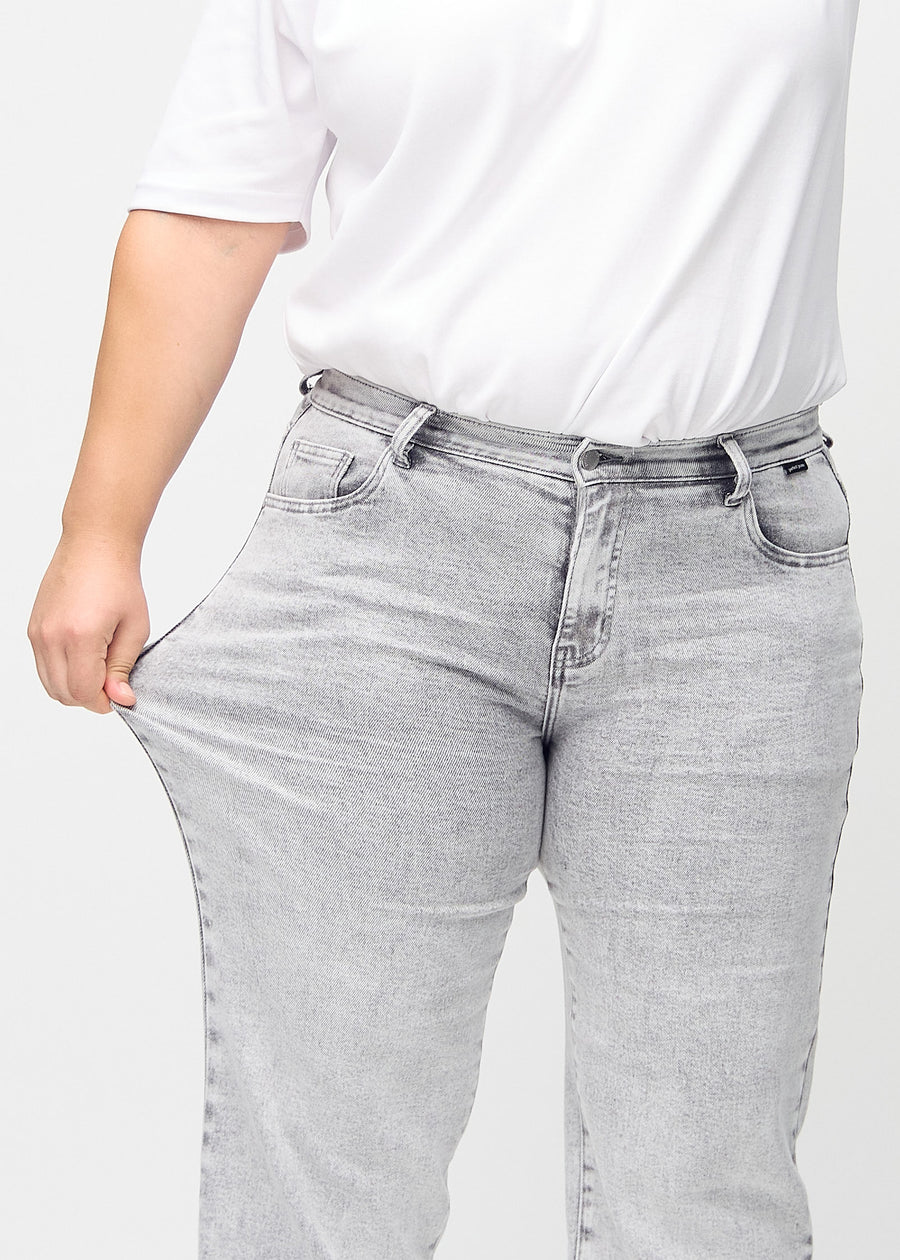 Loose-Jeans für Damen in Hellgrau, Farbe Ashes. Ein Plus-Size-Model dehnt den Jeansstoff am Oberschenkel, um den Stretch zu zeigen.