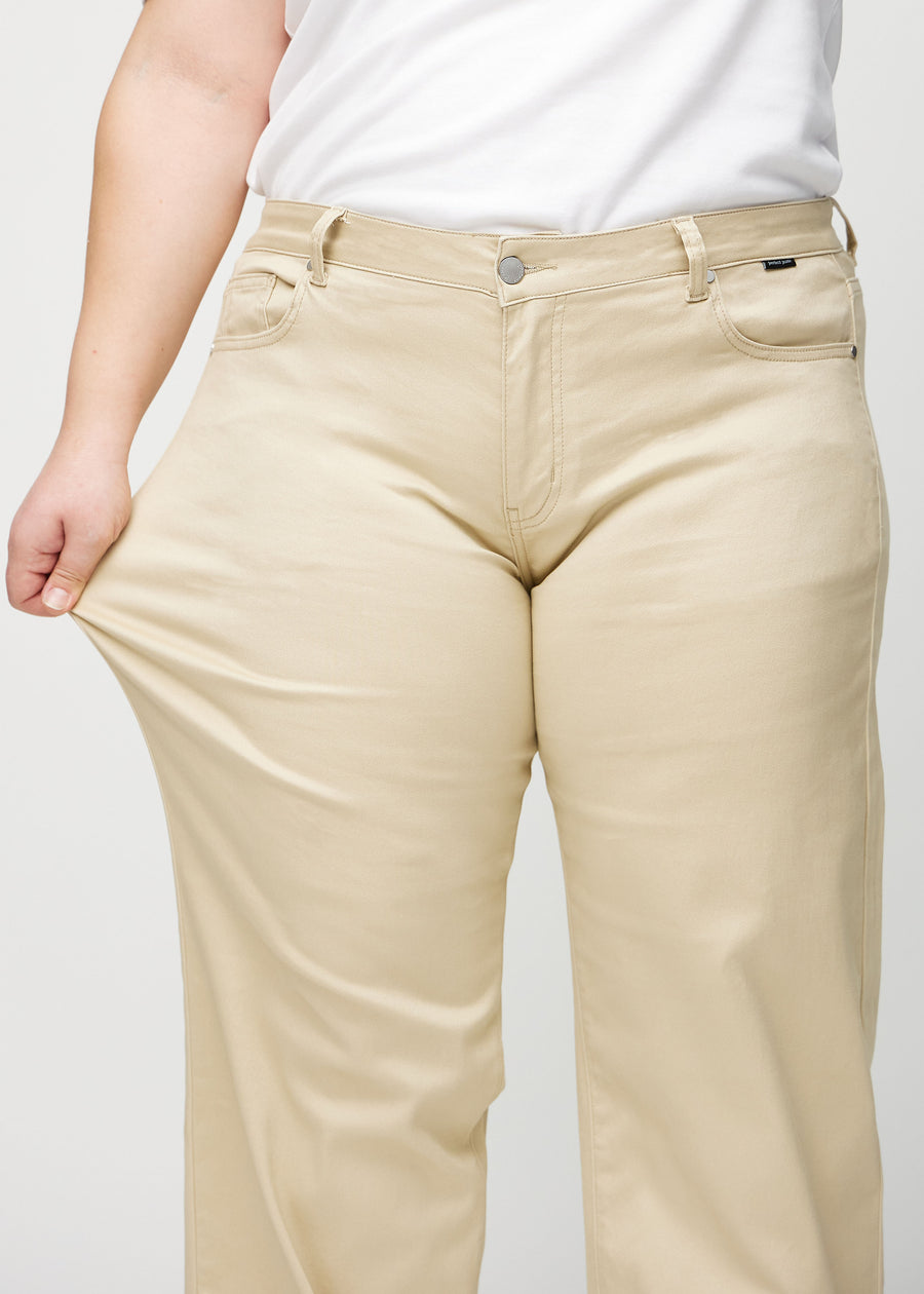 Loose-Jeans für Damen in Beige, Farbe Gazelles. Ein Plus-Size-Model dehnt den Jeansstoff am Oberschenkel, um den Stretch zu zeigen.