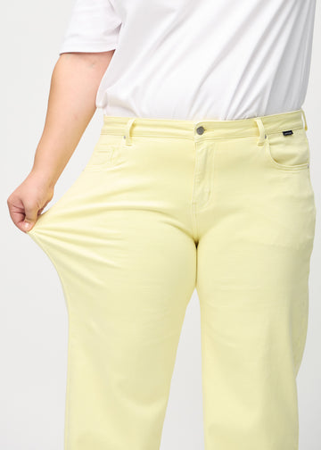 Loose-Jeans für Damen in Hellgelb, Farbe Lemonades. Ein Plus-Size-Model dehnt den Jeansstoff am Oberschenkel, um den Stretch zu zeigen.