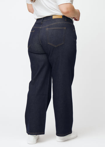 Tief dunkelblaue Denim jeans für Damen in der Farbe Midnights, von hinten an einem Plus-Size-Model gezeigt.