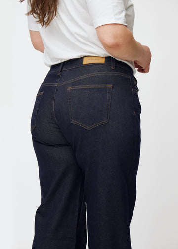 Tief dunkelblaue Denim jeans für Damen in der Farbe Midnights, von hinten als Nahaufnahme an einem Plus-Size-Model gezeigt.