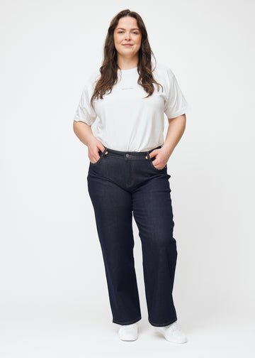 Ganzkörperbild eines Plus-Size-Models in tief dunkelblauer Denim jeans für Damen in der Farbe Midnights mit loose Passform.