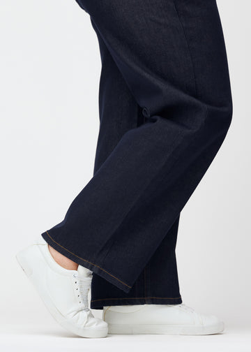 Tief dunkelblaue Denim jeans für Damen in der Farbe Midnights mit loose Passform, als Nahaufnahme an den Knöcheln eines Plus-Size-Models gezeigt, um den weiten Abschluss zu zeigen.