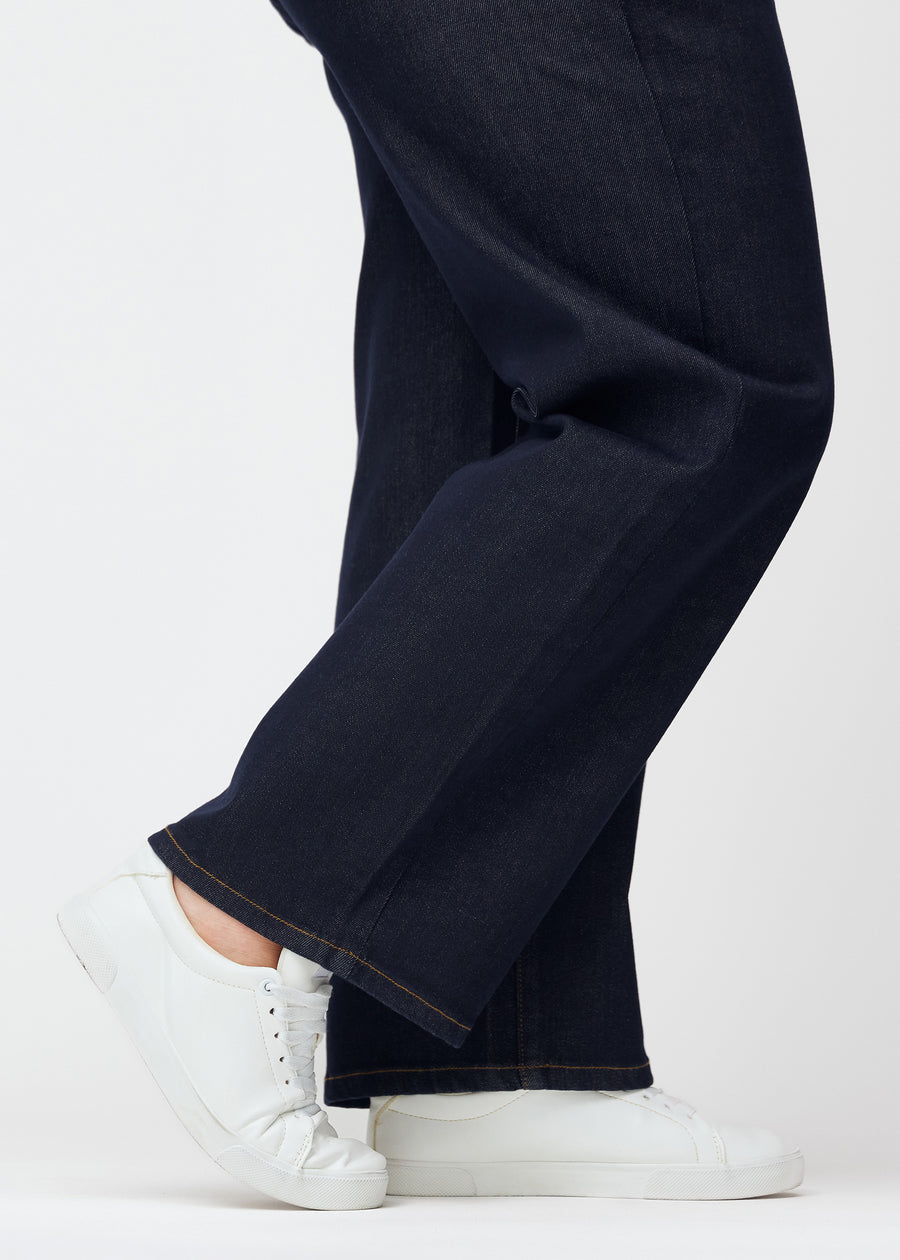 Tief dunkelblaue Denim jeans für Damen in der Farbe Midnights mit loose Passform, als Nahaufnahme an den Knöcheln eines Plus-Size-Models gezeigt, um den weiten Abschluss zu zeigen.