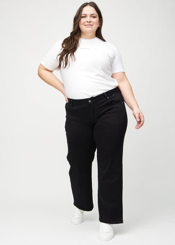 Ganzkörperbild eines Plus-Size-Models in schwarzen loose jeans.