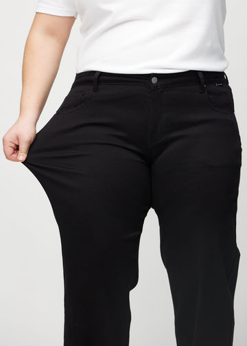 Das Plus-Size-Model zieht die Jeans am Oberschenkel auseinander, um den Stretch zu zeigen.