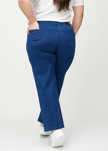 Dunkelblaue loose jeans von hinten an einem Plus-Size-Model gesehen, damit man das gesamte Produkt sehen kann.